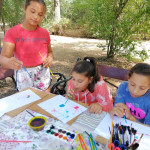 Városi Humánsegítő és Szociális Szolgálat | Galéria Gyerekek festenek egy kültéri padon.