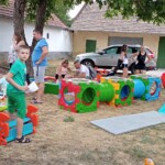 Városi Humánsegítő és Szociális Szolgálat | Galéria Játszó gyerekek és szüleik egy udvaron.