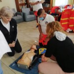 Városi Humánsegítő és Szociális Szolgálat | Újraélesztési gyakorlat az Idősek Otthonában Mentős előadáson résztvevő emberek.
