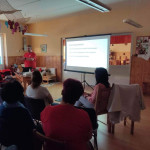 Városi Humánsegítő és Szociális Szolgálat | Elsősegélynyújtás kisgyermekkorban-szülőcsoportos megbeszélés a Bölcsődében Egy mentős előadása egy teremben.