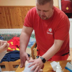 Városi Humánsegítő és Szociális Szolgálat | Elsősegélynyújtás kisgyermekkorban-szülőcsoportos megbeszélés a Bölcsődében Mentős mutat be újraélesztést gyermekalakú babán.