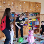 Városi Humánsegítő és Szociális Szolgálat | Farsang a bölcsődében Farsang alkalmából jelmezben lévő felnőttek és gyermekek táncolnak.