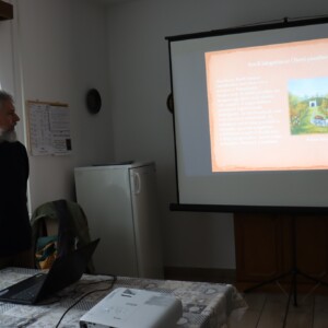 Városi Humánsegítő és Szociális Szolgálat | Galéria Férfi előadást tart háttérben a kivetített dokumentum.