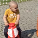 Egy piros motorral j&aacute;tsz&oacute; kisfi&uacute;.