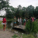 Városi Humánsegítő és Szociális Szolgálat | Napközis tábor a Családsegítőben Több fiatal áll egy mólón a víz parton.