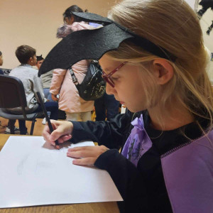 Városi Humánsegítő és Szociális Szolgálat | Halloween a Gyermekjóléti Szolgálatnál Egy kislány rajzol denevérjelmezben.