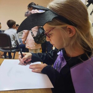 Városi Humánsegítő és Szociális Szolgálat | Halloween a Gyermekjóléti Szolgálatnál Egy kislány rajzol denevérjelmezben.