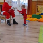 Városi Humánsegítő és Szociális Szolgálat | Mikulás várás a bölcsődében A Mikulás egy kisfiúnak ad át egy ajándékot.