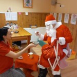 Városi Humánsegítő és Szociális Szolgálat | Mikulás várás a bölcsődében A Mikulást sütivel és tejjel kínálja egy kisgyermeknevelő.