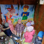 Egy csapat kisgyerek élvezi a játékot egy színes, szeszélyesen berendezett fából készült játszóházban, vidám festményekkel és puha játékokkal.