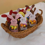 Ünnepi húsvéti kosár, tele színes papír nyuszikkal, akik fóliába csomagolt csokitojást tartanak.