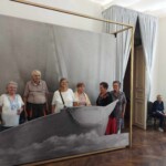 Városi Humánsegítő és Szociális Szolgálat | Galéria Idősek csoportképe egy hajós háttér előtt.