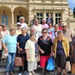 Városi Humánsegítő és Szociális Szolgálat | Galéria Idősek csoportképe egy kastély előtt.