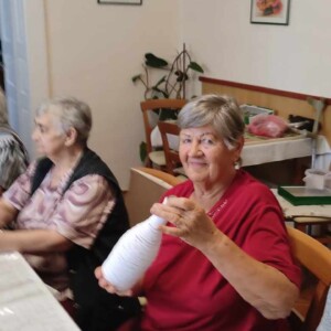 Városi Humánsegítő és Szociális Szolgálat | Galéria Üvegdíszt tartó idős hölgy.