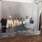 Városi Humánsegítő és Szociális Szolgálat | Galéria Idősek csoportképe egy hajós háttér előtt.