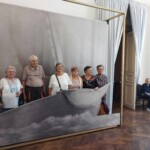 Városi Humánsegítő és Szociális Szolgálat | Galéria Idősek csoportképe egy hajós háttér előtt.