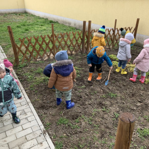 Gyermekek kertészkednek a Bölcsőde kertjében.