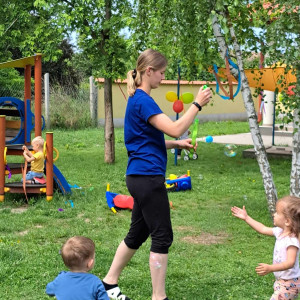 A kisgyermeknevelő buborékokat fúj a körülötte álló gyermekeknek.