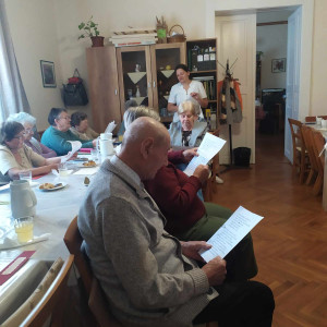 Városi Humánsegítő és Szociális Szolgálat | Anyák napja Vereset olvasó idősek egy asztalnál.