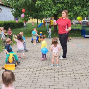 Városi Humánsegítő és Szociális Szolgálat | Gyermeknap a bölcsődében A kisgyermeknevelő buborékokat fúj az udvaron játszó gyerekeknek.