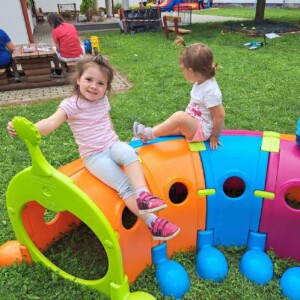 Városi Humánsegítő és Szociális Szolgálat | Gyermeknap a bölcsődében Kültéri bújós játékkal játszó gyermekek.