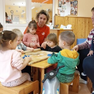 gyerekek j&aacute;tszanak egy fa asztalon konyhai eszk&ouml;z&ouml;kkel.