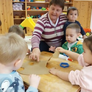 gyerekek j&aacute;tszanak egy fa asztalon konyhai eszk&ouml;z&ouml;kkel.