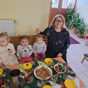 Egy kisgyermeknevelő gyerekekkel ül egy karácsonyi asztalnál